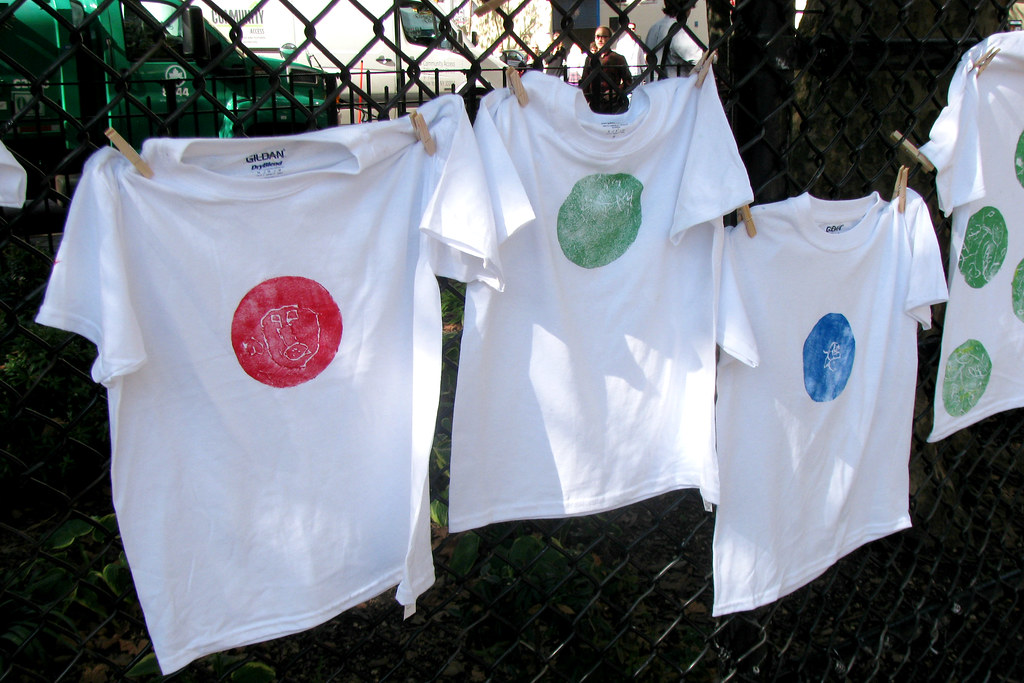 Poleras blancas estampadas colgadas de una reja