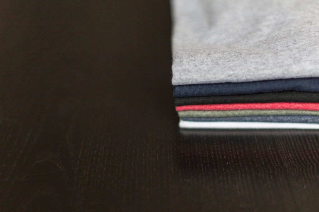 Pila de poleras de colores sobre una mesa oscura